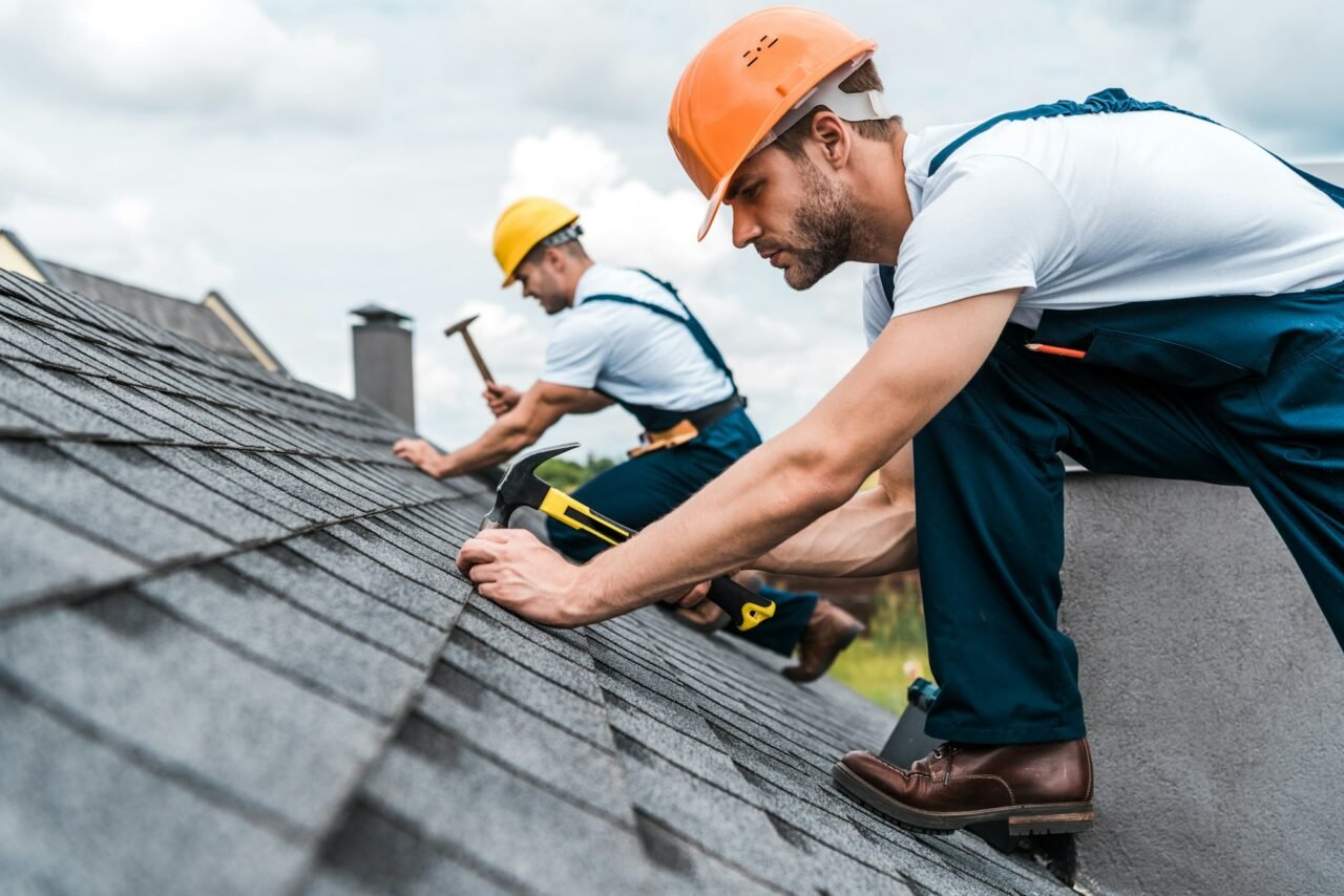 selective focus of handsome handyman repairing roof with coworker.jpg